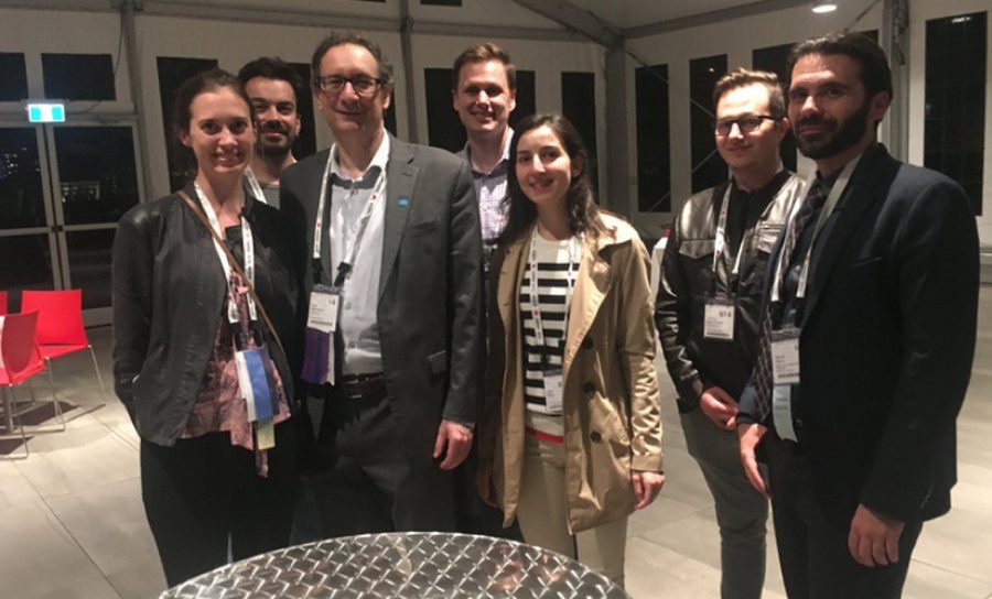 Seven members of the MRM Highlights team standing together at an
                      evening reception, wearing conference badges.